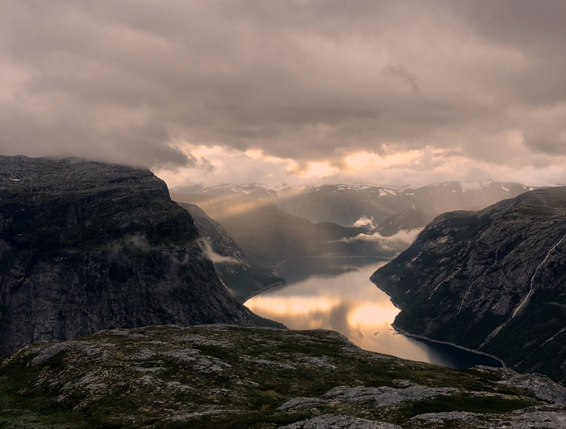 A photograph of a river flowing through the mountains on a cloudy day